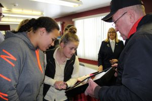 two high school students gaze upon war medals held by a veteran