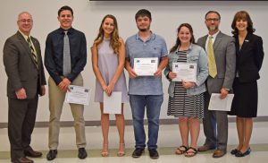 Four students stand with three adults