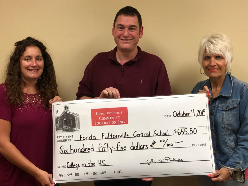 two school counselors and a school board member hold a large check