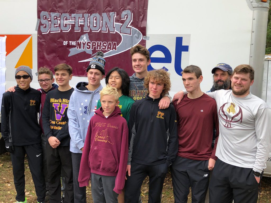 cross country teammates and their coaches pose in front of a Section 2 banner