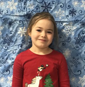 kindergarten student in front of a snowflake backdrop