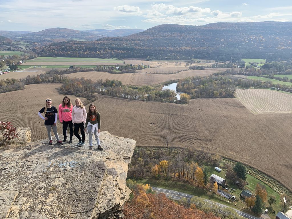 four students stand on a ledge overlooking the Mohawk Valley
