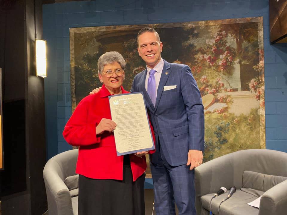 an educator holds a certificate while posing with an assemblyman