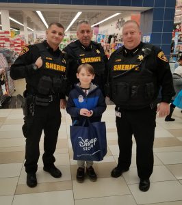 three sheriff's deputies and a third grade pose in a mall