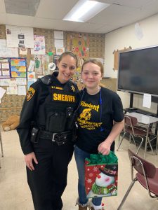 a school resource officer and a freshman pose with a holiday gift bag
