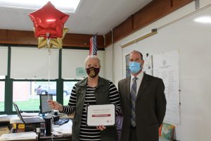 high school math teacher and school superintendent hold up a certificate and balloons