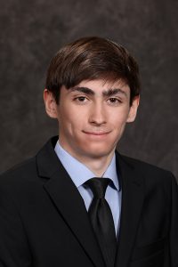 portrait of a high school student wearing a suit and tie with short dark hair