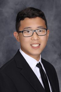 portrait of a high school student wearing glasses and a suit and tie with short dark hair