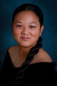 portrait of a high school student wearing a black top with long dark hair in a braid