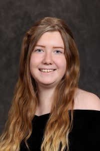 portrait of a high school student wearing a black top with long strawberry blonde hair
