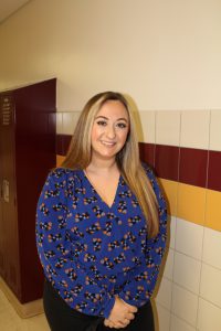 portrait of a high school teacher standing in a school hallway