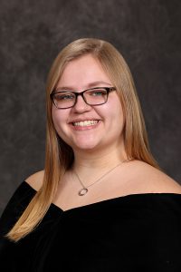 portrait of a high school student wearing glasses and a black top with long blonde hair