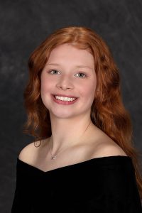 portrait of a high school student wearing a black top with long red hair